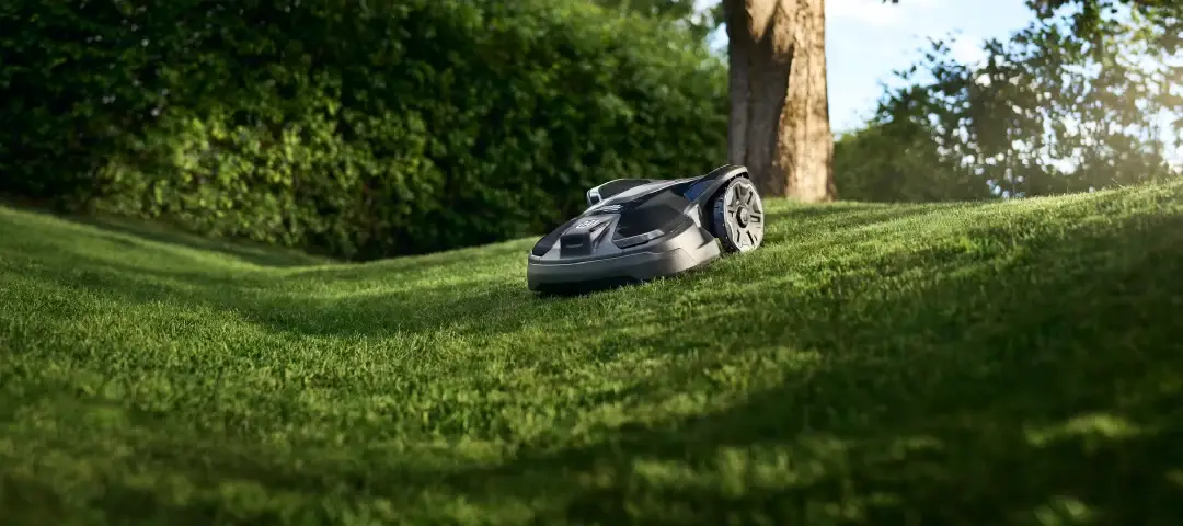 Husqvarna 320 automower op heuvelachtig grasveld - detuinmachine.nl